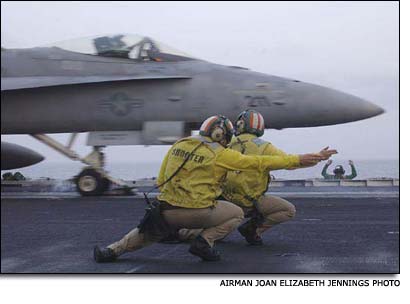 A pair of “yellow shirts” signaling the launch of a U.S. Navy F/A-18 Hornet