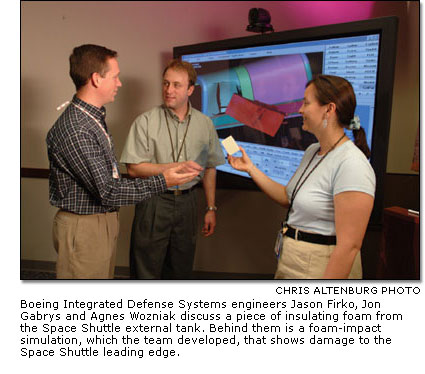 Boeing Integrated Defense Systems engineers discuss a piece of insulating foam from the Space Shuttle external tank.