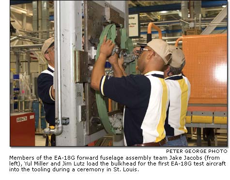 Jake Jacobs, Yul Miller and Jim Lutz load the bulkhead for the ?rst EA-18G test aircraft into the  tooling