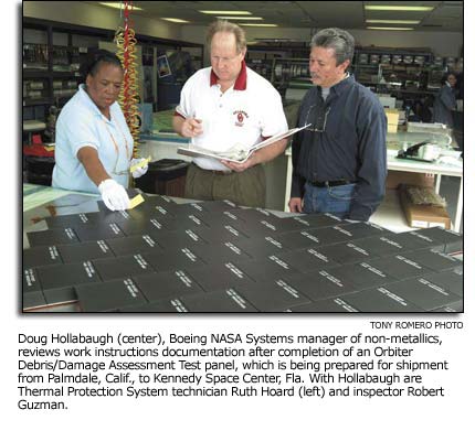 Doug Hollabaugh, Ruth Hoard and Robert Guzman standing over an Orbiter Debris/Damage Assessment Test panel