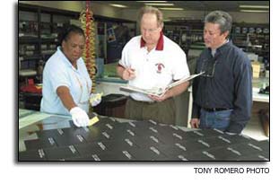 Doug Hollabaugh, Ruth Hoard and Robert Guzman standing over an Orbiter Debris/Damage Assessment Test panel