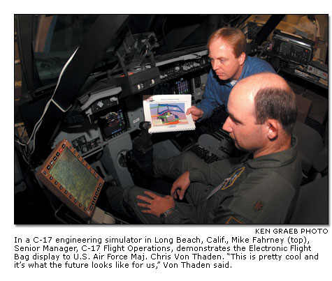 In a C-17 engineering simulator, Mike Fahrney demonstrates the Electronic Flight Bag display to U.S. Air Force Maj. Chris Von Thaden.