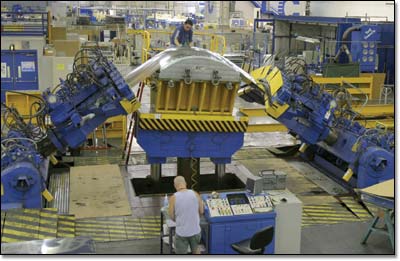 Stretch press operators Ron Wester and Dave Morriss position the enormous jaws of the machine to pull and form aluminum sheet over a die to produce complex parts.