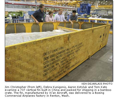 Jim Christopher Debra Kunigonis, Aaron Kotyluk and Tom Kato examine a 737 vertical fin built in China and packed for shipping in a bamboo crate.