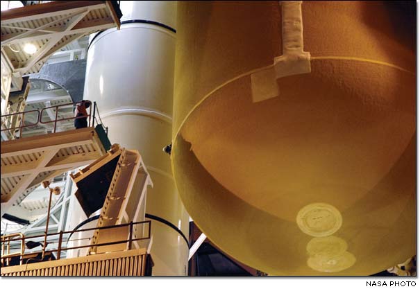 a technician watches the progress of the External Tank as it is lowered between the Solid Rocket Boosters (SRBs) on the Mobile Launcher Platform