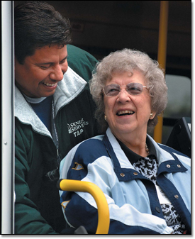 Ed Salinas helps client Goldie Wolfla into a van