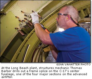 Structures mechanic Thomas Barber drills out a frame splice on the C-17's center fuselage