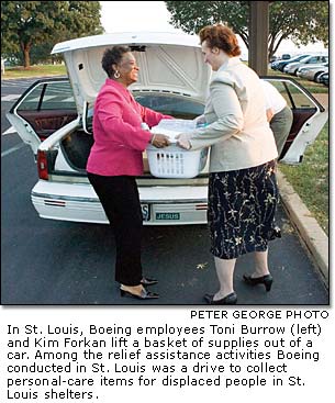 Boeing employees Toni Burrow and Kim Forkan lift a basket of supplies out of a car