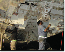 David Cabello (left) of the U.S. Air Force Combat Logistics Support Squadron and Boeing teammate Pat Roche remove sections of the damaged C-17 aircraft