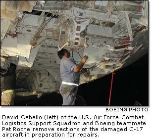 Boeing employees remove sections of the damaged C-17 aircraft in preparation for repairs